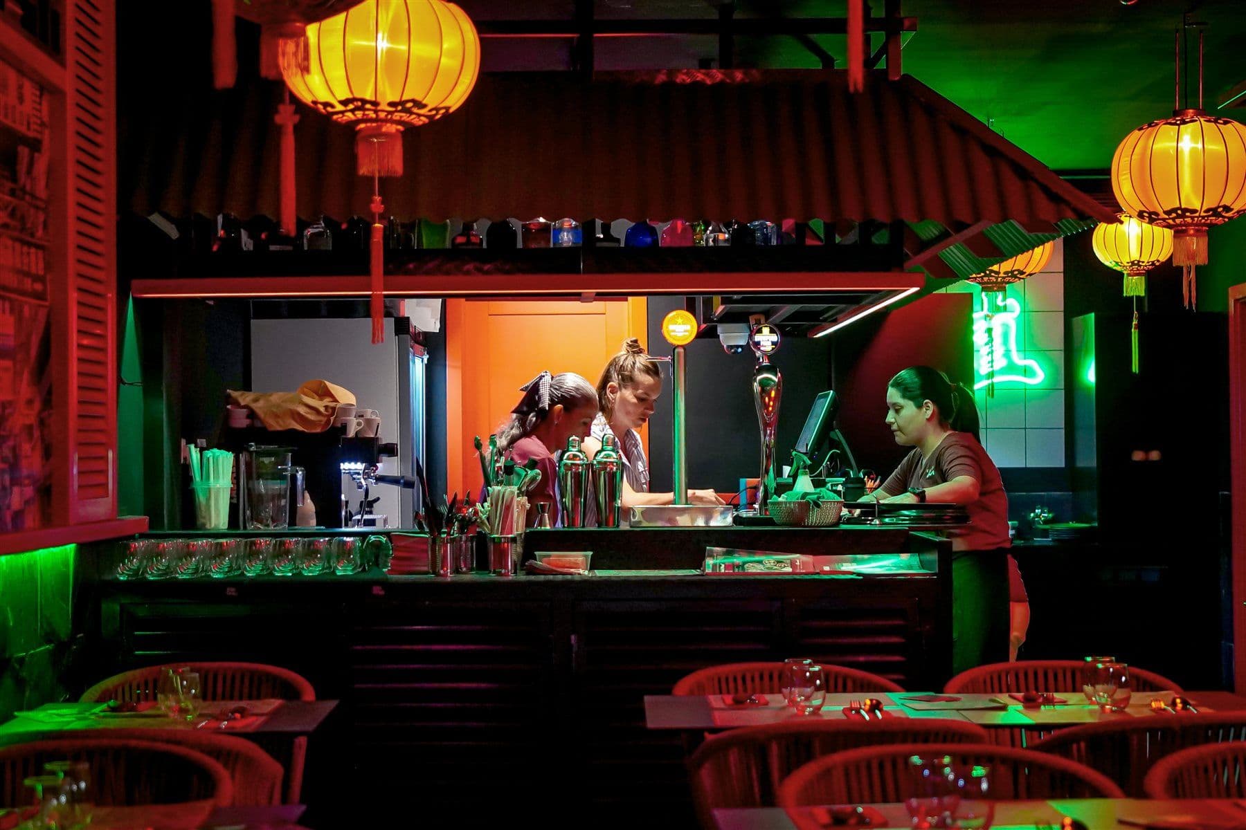 Barra de Mrs Miyagi's con la cocina a la vista, faroles de papel y neón verde