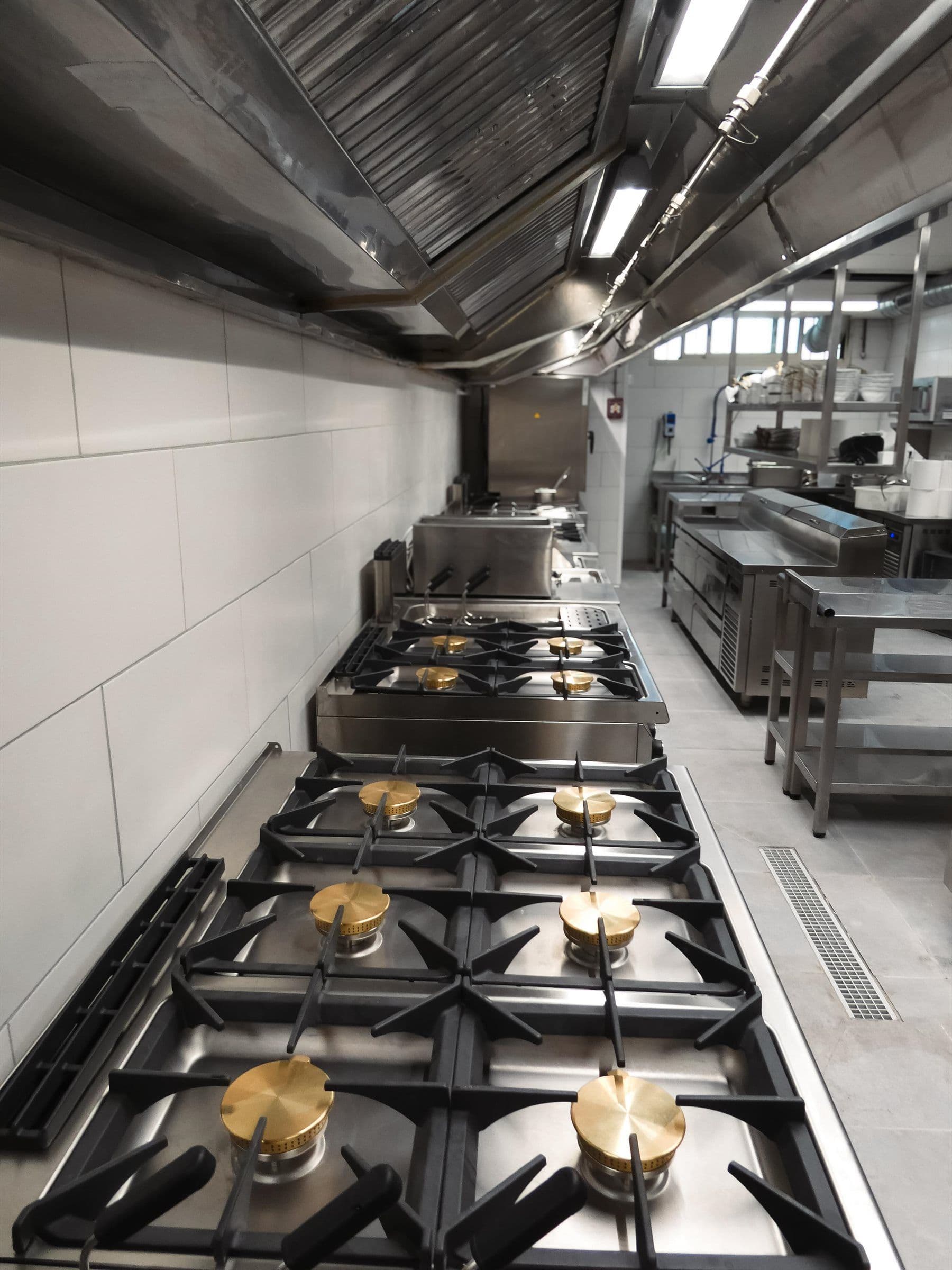 Línea de cocción a gas ya instalada en la cocina de Bianco, con la campana de extracción sobre los fuegos